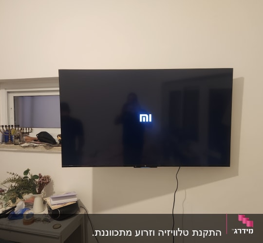 טלוויזיה מותקנת על קיר עם חוט חשמל גלוי